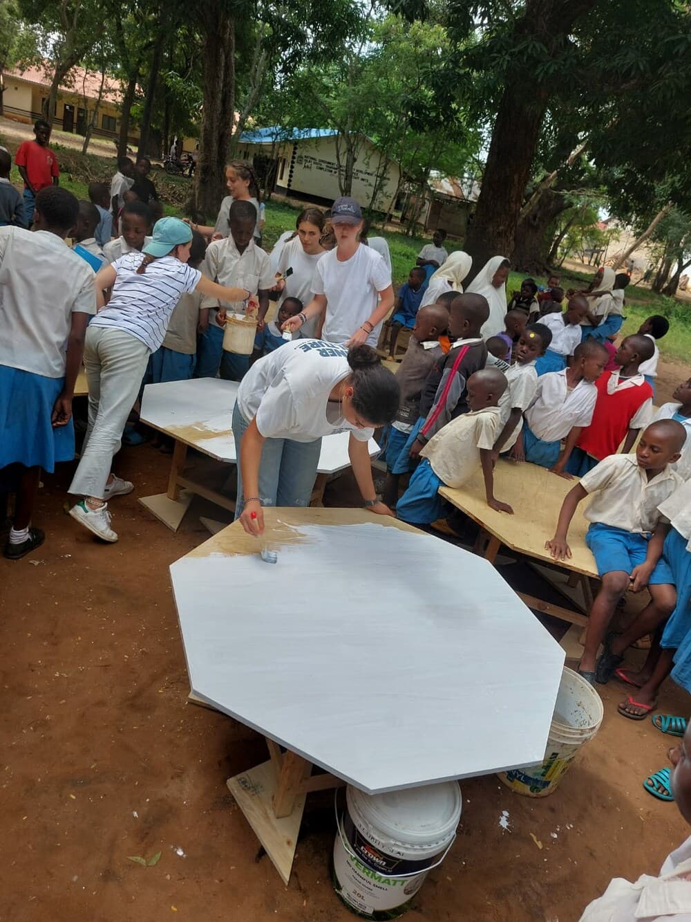 Volunteers and students painting new school desks at Shariani